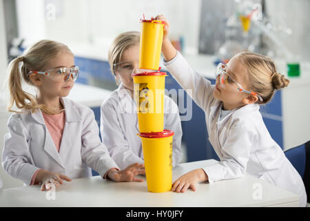 Trois enfants en portant un sarrau de laboratoire de sciences et de s'amuser Banque D'Images