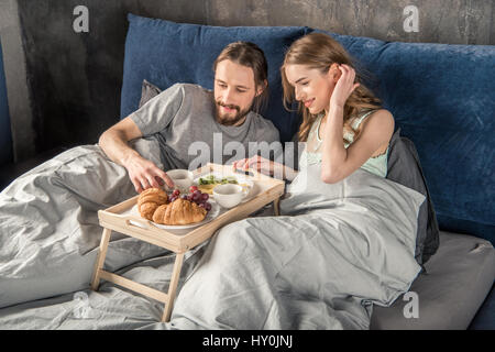 Happy young couple a un petit déjeuner au lit Banque D'Images