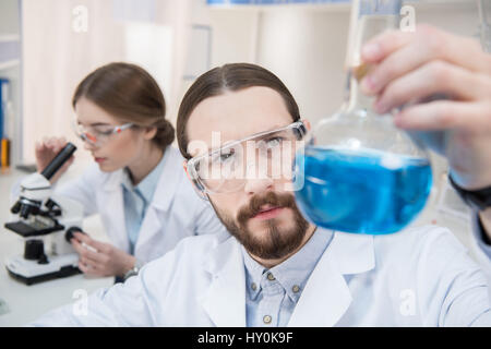 Pensive male scientist holding flask avec réactif chimique Banque D'Images