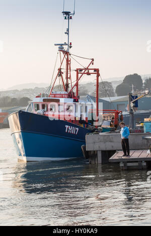 Un chalutier de Teignmouth, station d'accueil pour décharger ses prises de poissons sur le quai de poisson à Teignmouth, Devon, UK. Deux jeunes hommes sont sur un ponton de pêche aussi. Banque D'Images