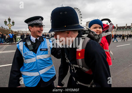 Un policier portant un bébé dans un porte-bébé, le pont de Westminster, London, UK Banque D'Images