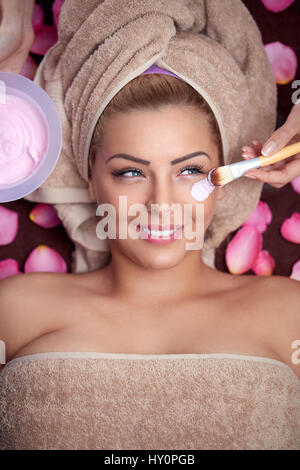 Belle jeune femme qui reçoit le masque facial hydratation à spa salon de beauté Banque D'Images