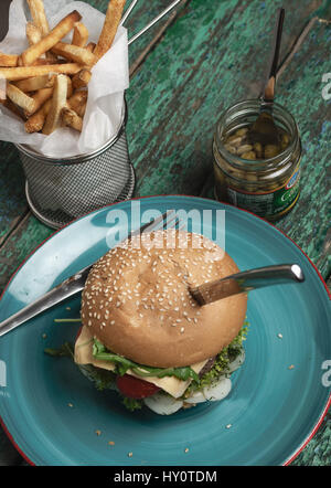 Fromage savoureux burger avec frites et les câpres sur fond rustique Banque D'Images