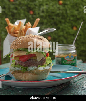 Fromage savoureux burger avec frites et les câpres sur fond vert Banque D'Images