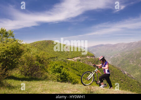 Femme mountainbiker poussant son mountainbike uphill Banque D'Images