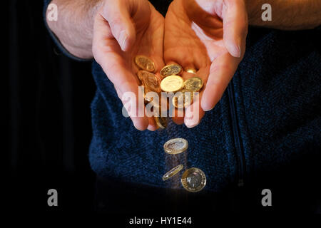 Pièces livre glisser entre les doigts Banque D'Images