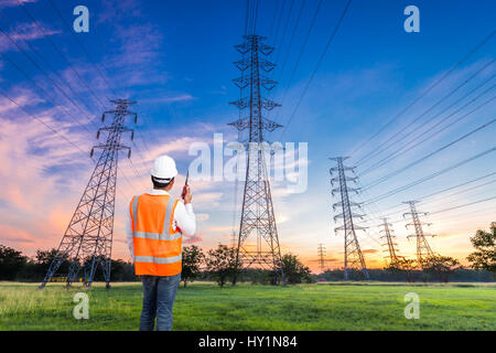 Ingénieur électrique avec l'électricité à haute tension pylône au lever de l'arrière-plan Banque D'Images