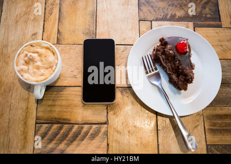 Coup de frais généraux de téléphone intelligent avec la tasse de café et pâtisserie sur la table Banque D'Images