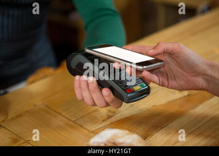 Close-up d'accepter des paiements par barista smart phone in coffee shop Banque D'Images