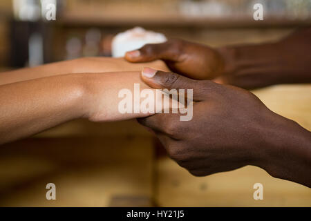 Close-up of multi ethnic couple holding hands in coffee house Banque D'Images