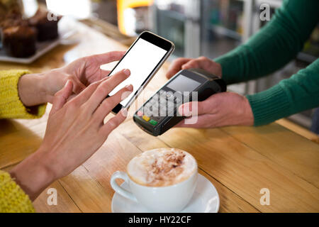 Image recadrée de barista acceptant les paiements par smart phone at cafe Banque D'Images