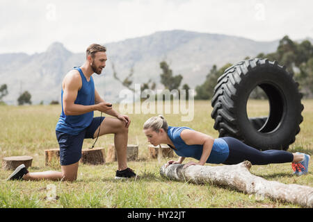 Mettre en place l'exécution de l'exercice pushup tandis que l'homme la mesure du temps dans boot camp Banque D'Images