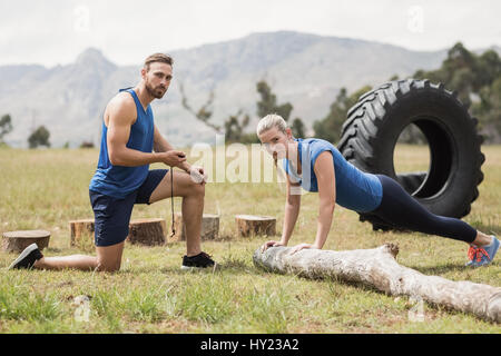 Mettre en place l'exécution de l'exercice pushup tandis que l'homme la mesure du temps dans boot camp Banque D'Images