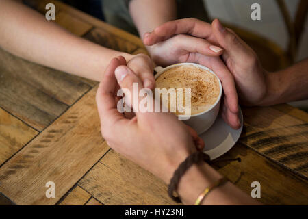 Close-up of couple holding hands and Coffee cup in cafeteria Banque D'Images