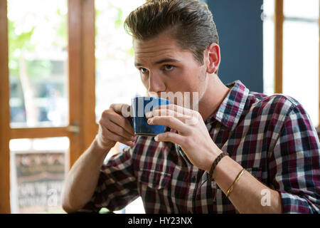 Beau jeune homme de boire du café dans la cafétéria Banque D'Images