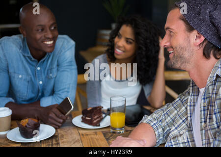 Heureux jeune homme en parlant avec des amis à table dans coffee house Banque D'Images