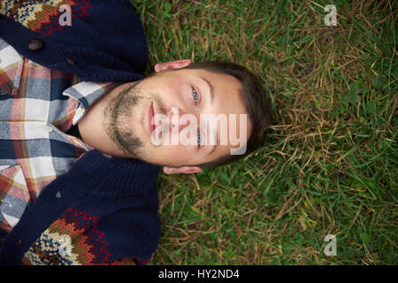 Smiling young man lying on grass in the Great outdoors Banque D'Images