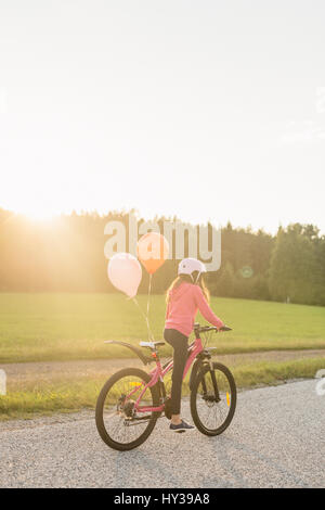 La Suède, Vastmanland, Hallefors, Bergslagen, Girl (10-11) équitation vélo au coucher du soleil Banque D'Images