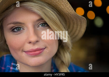 Portrait of young woman wearing hat in coffee shop Banque D'Images