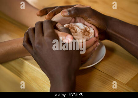 Close-up of couple holding hands and Coffee cup in coffee shop Banque D'Images