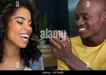 Jeune homme aimant le dessert pour alimentation femme en coffee shop