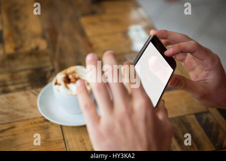 Close-up of man mains photographier par café smart phone in cafe Banque D'Images