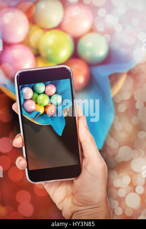 Hand holding mobile phone contre fond blanc contre les oeufs de pâques en chocolat coloré napkin Banque D'Images