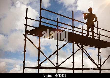 Thoughtful worker carrying planches en bois contre le ciel bleu avec des nuages blancs Banque D'Images