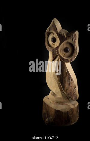 Owl sculpté sur bois naturel tronc isolé sur fond noir Banque D'Images