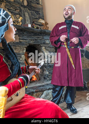 Couple en costume traditionnel l'exécution d'une chanson folklorique géorgiens en Ushguli Guest House, Ushguli, village de montagne du Caucase. Banque D'Images