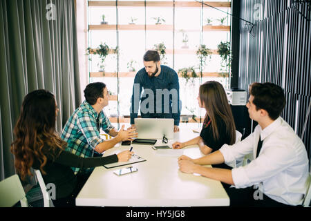 Jeune groupe de personnes de discuter de plans d'affaires dans un bureau moderne. Banque D'Images