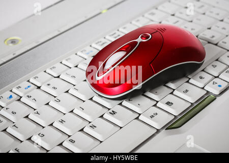 Une belle souris sans fil rouge sur le clavier blanc d'un ordinateur portable. Profondeur de champ Banque D'Images