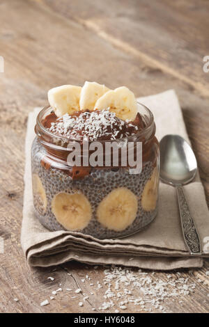 Chia pudding au chocolat smoothie banane dans un bocal en verre sur le vieux fond de bois Banque D'Images