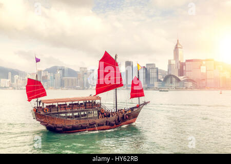 La fin de l'après-midi de soleil sur Hong Kong skyline with traditional Chinese junk ship crossing Victoria Harbour dans Tsim Sha Tsui. Le rendu HDR. Banque D'Images