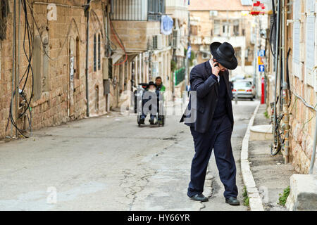 Jérusalem, Israël - 29 décembre 2016 : juif orthodoxe man with mobile phone à pied dans la rue au quartier juif à Jérusalem. Banque D'Images