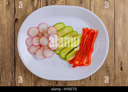 Tranches de légumes frais se situent sur une plaque sur un fond de bois. Les légumes assaisonnés d'épices : sel, poivre noir et rouge, ainsi qu'à la légère Banque D'Images
