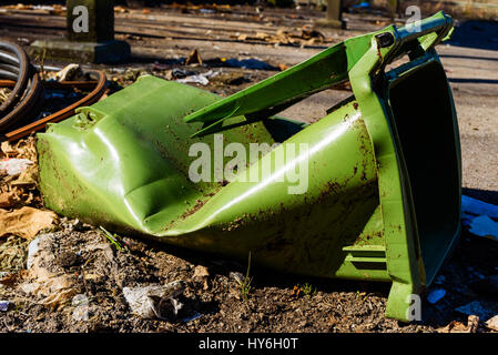 Brisée et déchirée trashcan vert couché sale sur le sol. Banque D'Images