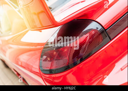 Arrière d'une voiture rouge dans la lumière du soleil Banque D'Images