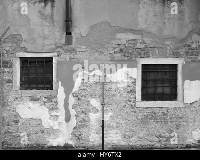 Old weathered brick wall avec plâtre cassé et deux fenêtres Banque D'Images