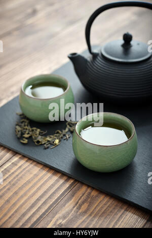 Le thé vert dans la théière avec de petites tasses sur fond de bois Banque D'Images