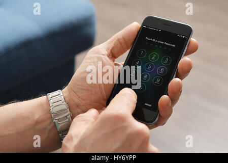 Kiev, Ukraine - Mars 06, 2016 : Un homme main tenant l'Apple iPhone 6 et entrez le code d'accès. Le téléphone cellulaire est produit par Apple Computer, Inc. Banque D'Images