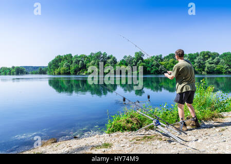 Aventures de pêche, pêche à la carpe. Pêche pêcheur avec carpfishing en eau douce, technique dans un beau jour d'été avec fond de ciel bleu Banque D'Images