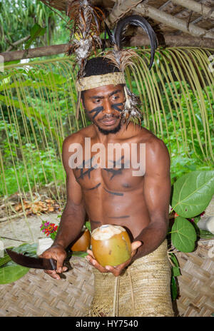 Ni-van (natif de Vanuatu ; courte pour les ni-Vanuatus) l'homme qui démontre l'ouverture d'une noix de coco avec une machette pour boire l'eau de noix de coco. [] Cesdeh Banque D'Images