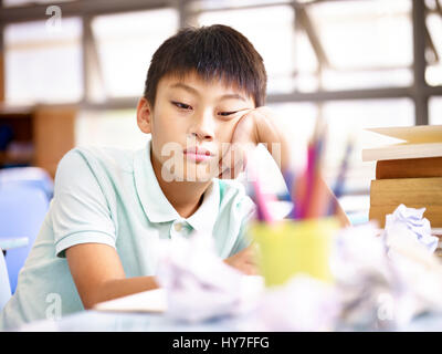 Triste et frustrée de l'école asiatique garçon assis seul en classe avec des morceaux sur 24. Banque D'Images