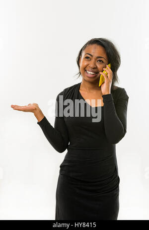 Une femme africaine parle d'un appareil mobile. Banque D'Images