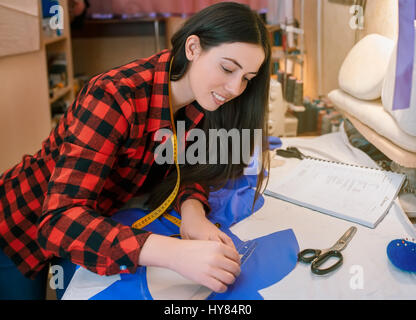 Jeune couturière faire motif sur tissu avec chalk tailleurs. Girl travailler avec un patron. Couture passe-temps comme une petite entreprise concept. Mea sur mesure Banque D'Images