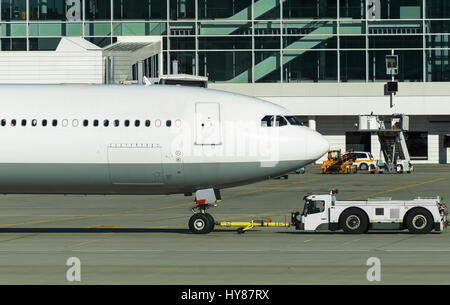 Tracteur remorqueur Pushback avec avion sur la piste de l'aéroport. Banque D'Images