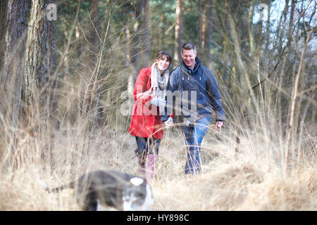 Un jeune couple marche main dans la main dans les bois Banque D'Images