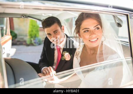 Une femme et un homme s'asseoir dans la voiture de mariage après son mariage Banque D'Images