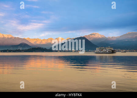 Le Lac Majeur, Laveno, Italie. Lever du soleil sur les Alpes enneigées. Dans l'arrière-plan le côté du Piémont avec la petite ville de Verbania Intra et Banque D'Images
